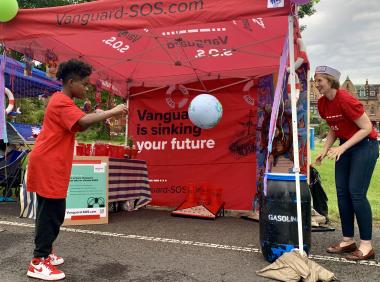 Young person dunks the "planet" into an oil drum in a game dramatizing climate impacts of Vanguard investments